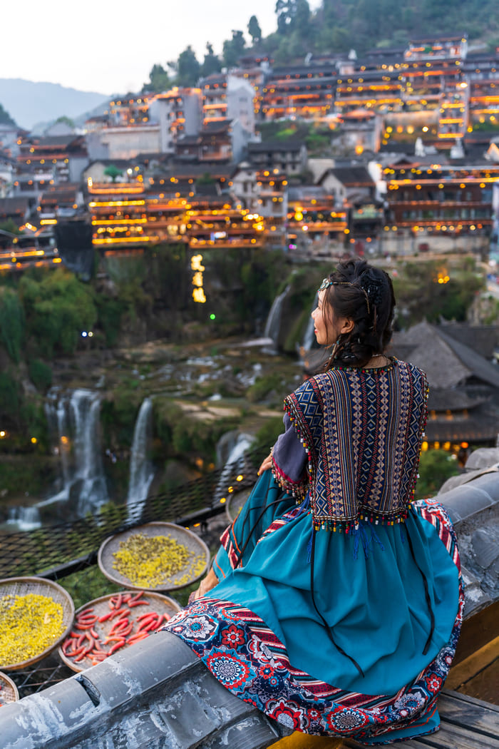 Mujer sentada de espaldas viendo un paisaje de China